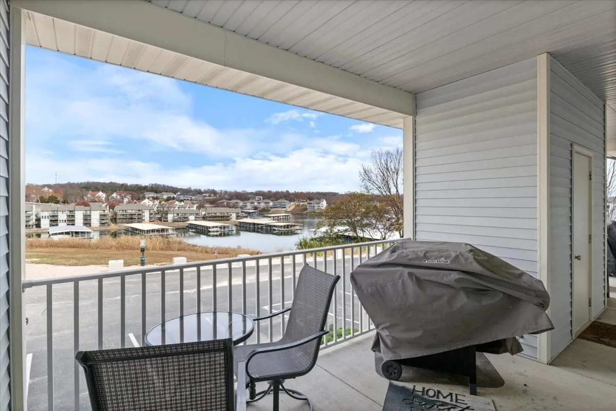 A serene patio area with comfortable seating and a grill overlooking the water, ideal for outdoor dining and socializing. The setting is highlighted by sunset views and a backdrop of the lake.