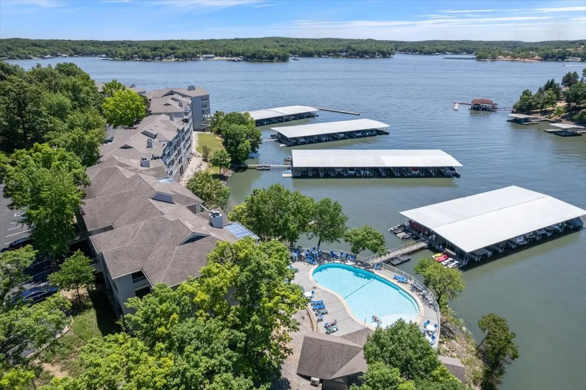 A scenic view featuring a sparkling swimming pool set against the backdrop of the expansive lake, boat docks, and surrounding greenery. The area looks peaceful and secluded, inviting couples to swim, sunbathe, or simply enjoy the sunset over the water.